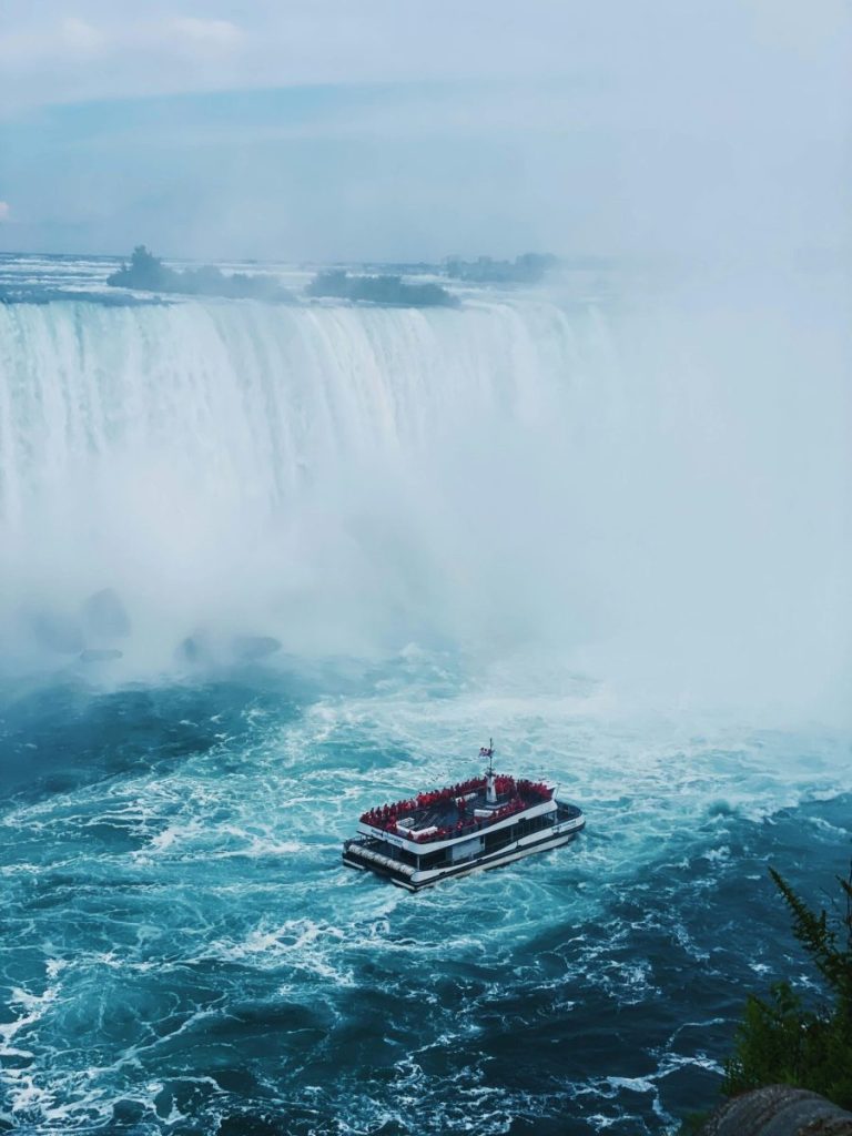 A tourist boat navigates the misty waters beneath the iconic Niagara Falls, Ontario, Canada.