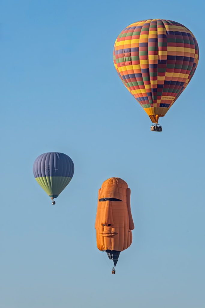 Three hot air balloons in a clear blue sky.